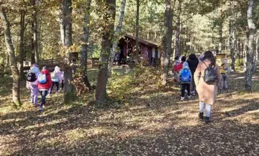 Dzieci spacerujące z nauczycielem po terenie Parku Korzonek w klimacie jesiennym