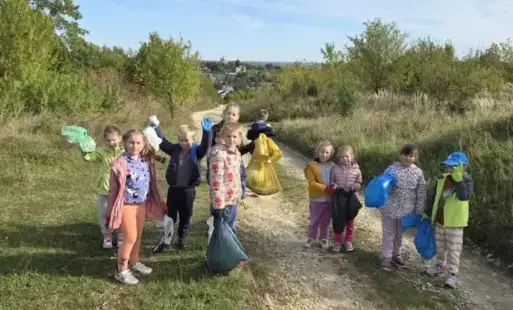 Grupa dzieci w rękawiczkach z workami na śmieci w terenie