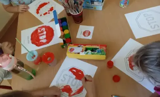 Dzieci malują farbkami czerwony znak STOP